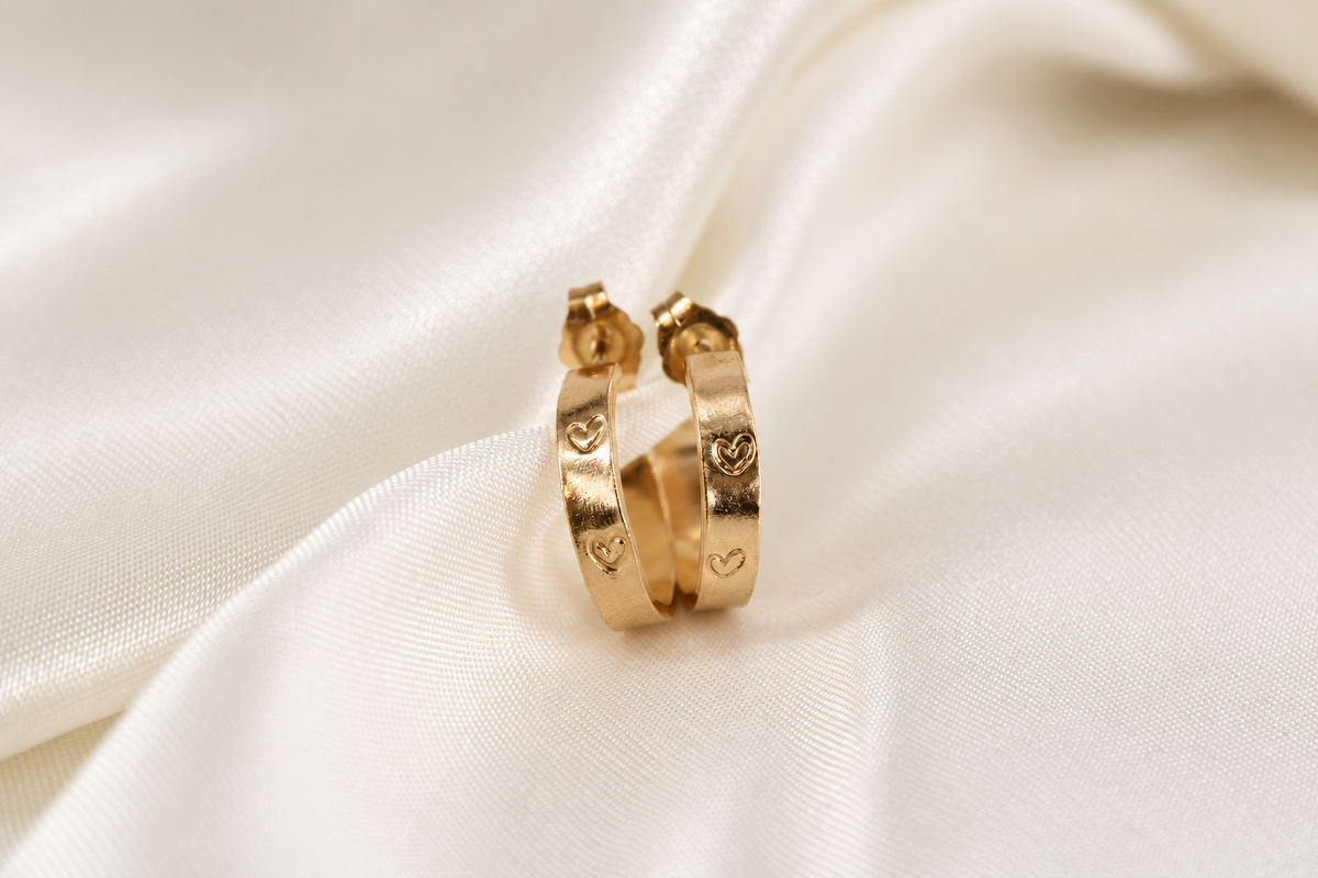 Pair of 15 mm gold-filled Beloved Micro Hoops with hand-stamped hearts on cream satin.