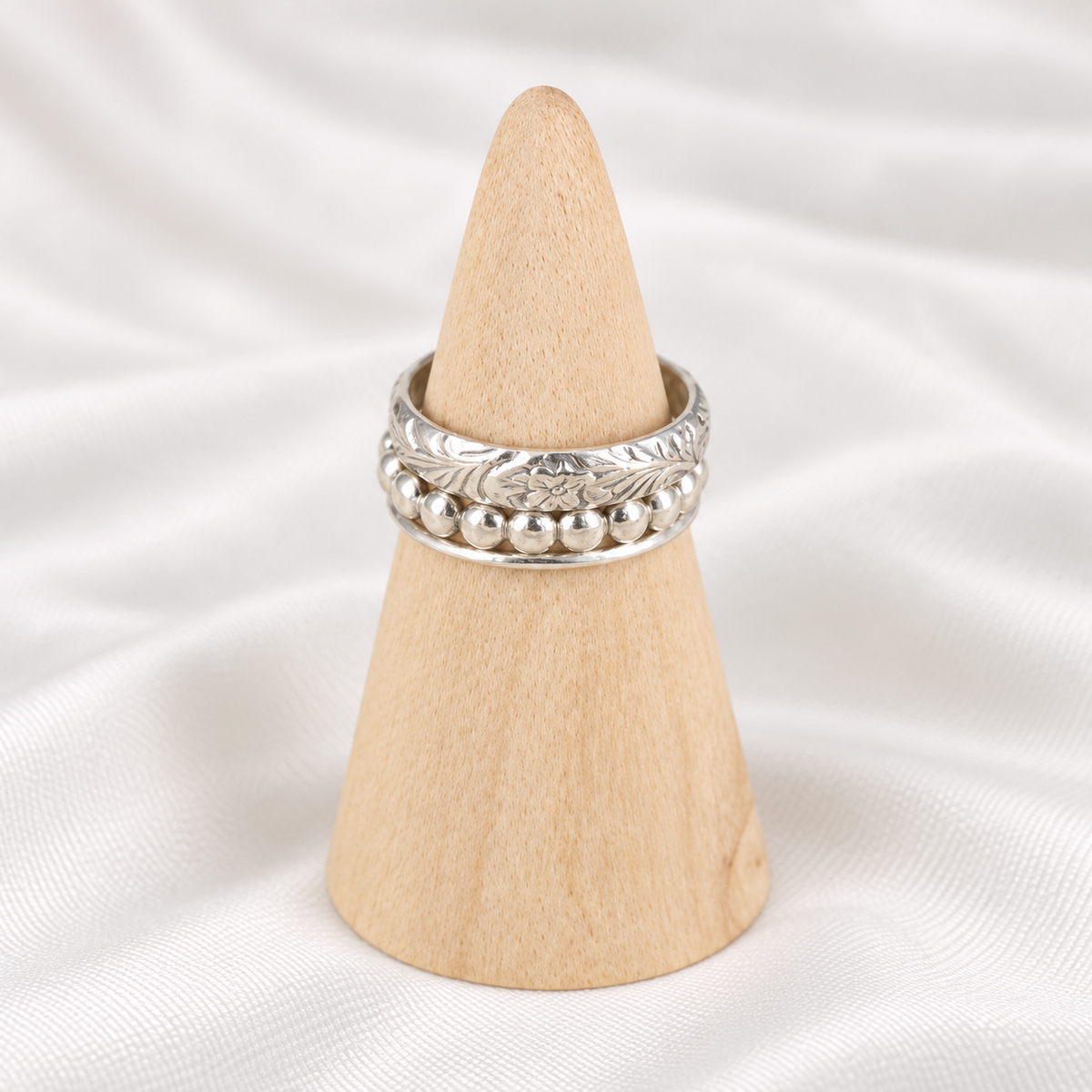 Handmade sterling silver stacker rings displayed on a natural wooden ring cone.