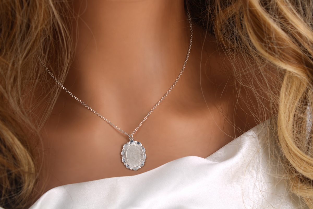 Silver floral medallion necklace on a delicate cable chain styled with a white satin blouse
