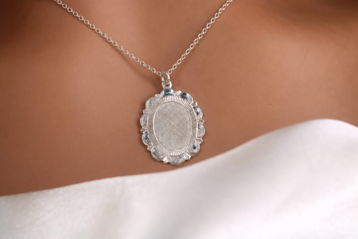 Close-up of a silver floral medallion pendant on a delicate sterling silver cable chain worn by a model