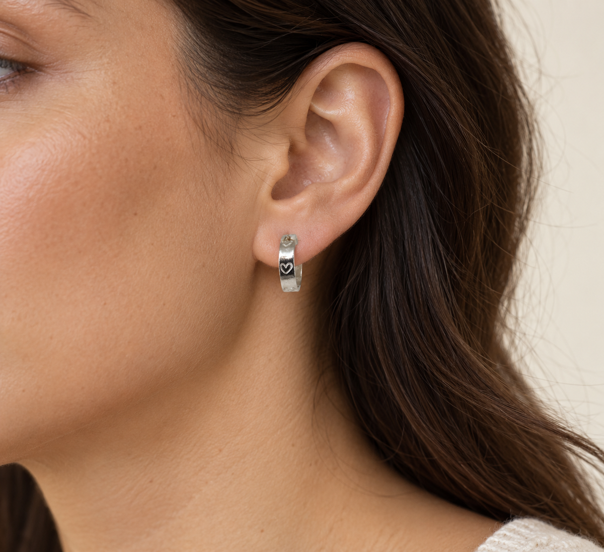 Side profile of a model wearing a 15 mm sterling-silver Beloved Micro Hoop with hand-stamped hearts.