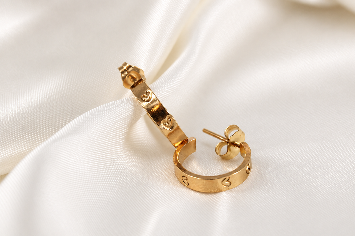 Open 15 mm gold-filled Beloved Micro Hoops showing the heart-stamped bands, posts, and butterfly backs on cream satin