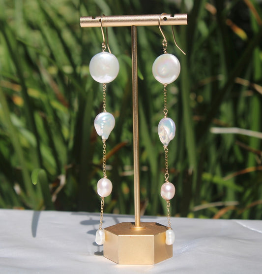 Cascading freshwater pearl shoulder-duster earrings with 14k gold-filled chain displayed on a gold stand