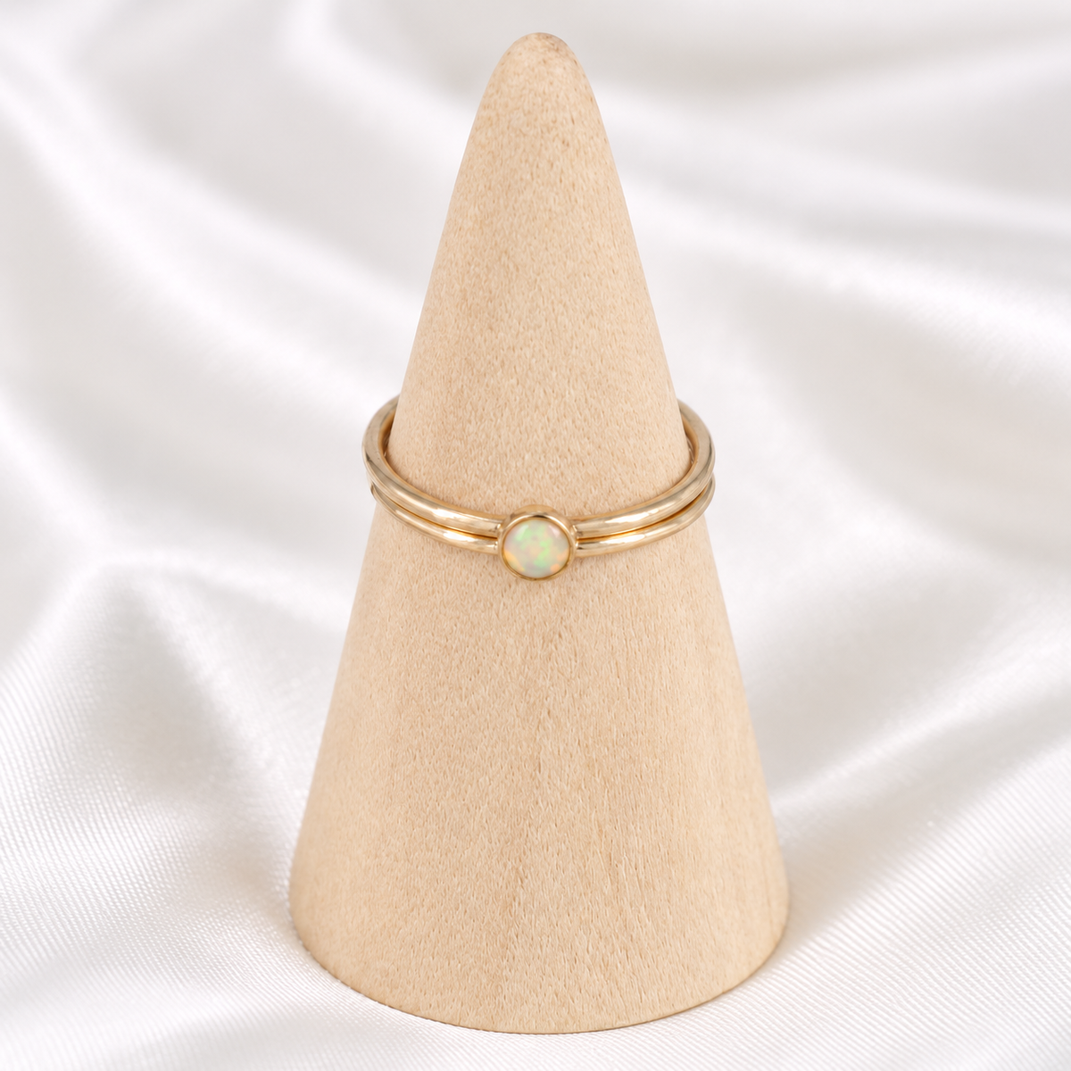 Dainty 14k gold-filled opal ring stack displayed on a natural wooden cone.