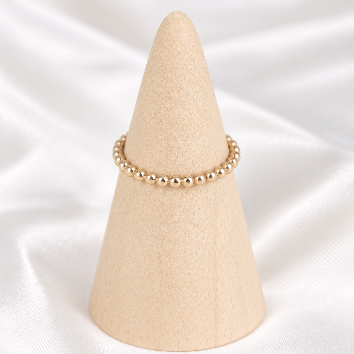Handmade 14k gold-filled beaded stacker ring displayed on a natural wooden cone.