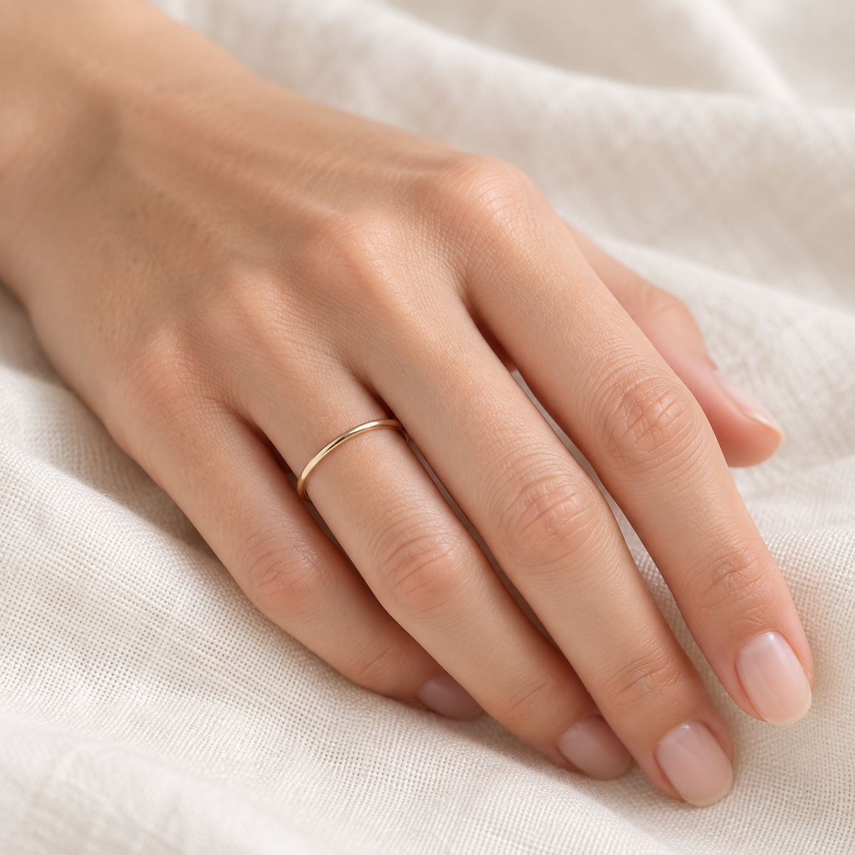 Delicate 18-gauge gold-filled minimalist ring worn alone on a model’s hand.