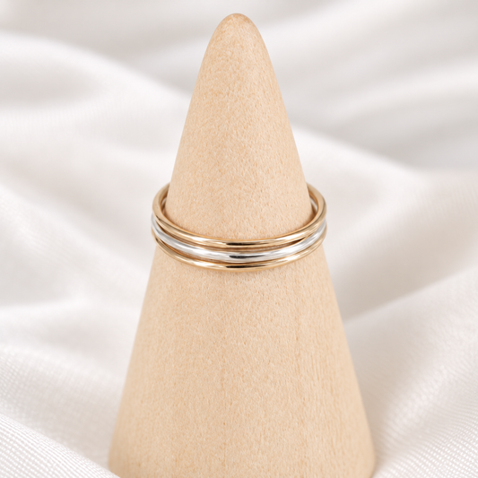 Thin mixed-metal minimalist ring stack displayed on a natural wooden cone.