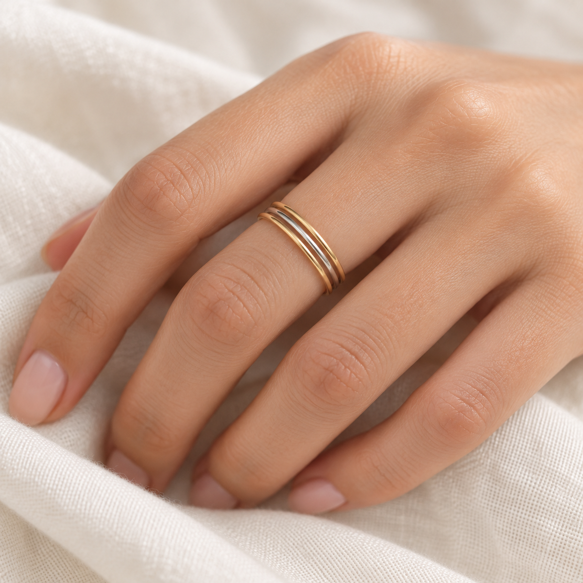 Mixed-metal minimalist three-ring stack worn on a model’s hand.